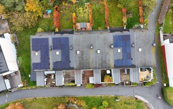 Fågelvy ovanför ett radhusområde med solceller på papptaket.