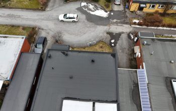 Fågelvy över på kedjehusets tak, efter takomläggning med asfaltpapp. Bredvid ligger grannhus.