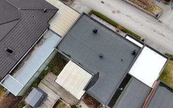 Fågelvy över kedjehus efter takomläggning med asfaltpapp. Runt huset ligger grannhus.