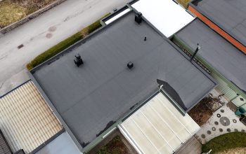 Fågelvy över kedjehus efter takomläggning med asfaltpapp. Runt huset ligger grannhus.