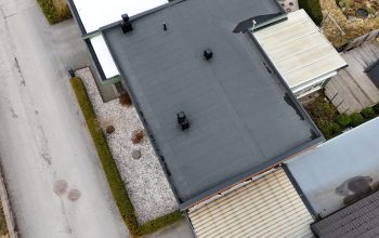 Fågelvy över kedjehus efter takomläggning med asfaltpapp. Runt huset ligger grannhus.