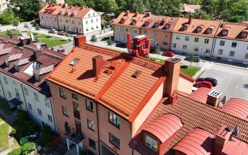 Fågelvy över ett lägenhetsområde. Längorna skiljs åt av bilvägar, och omges av gräsmattor. Taken varierar i färg och material.